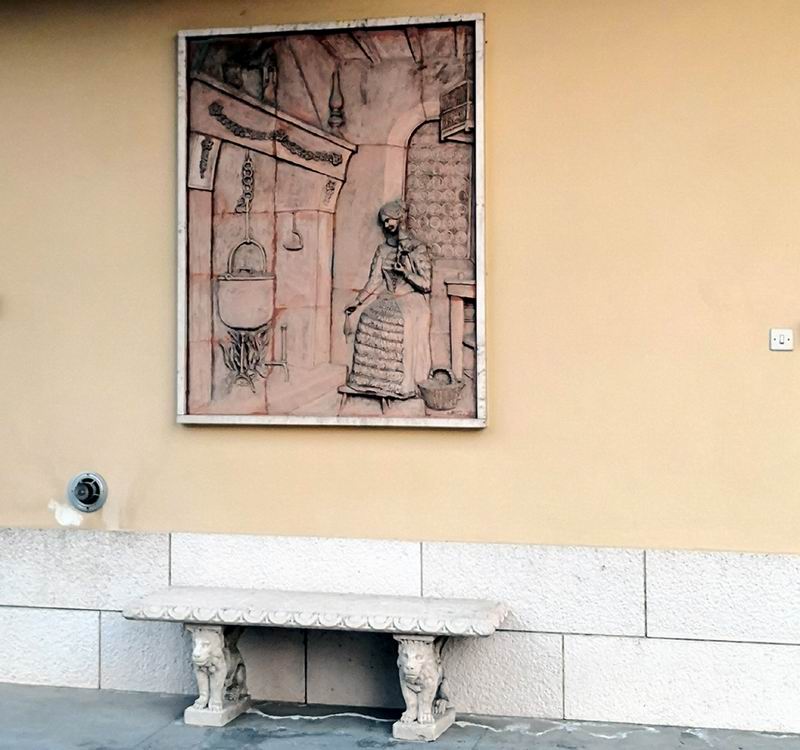 immagine di grande bassorilievo raffigurante una donna seduta davanti al camino Dama con Calderone